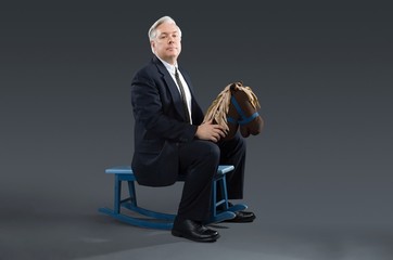 A businessman sat on a rocking horse